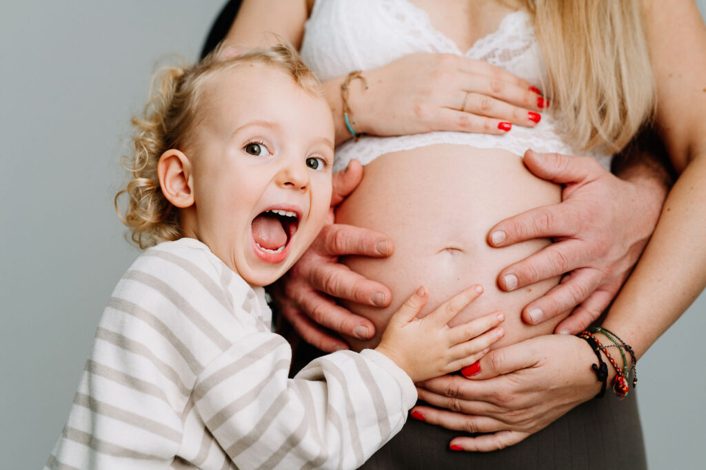 Kugelrunder Babybauch und eine Schwester, die sich freut.