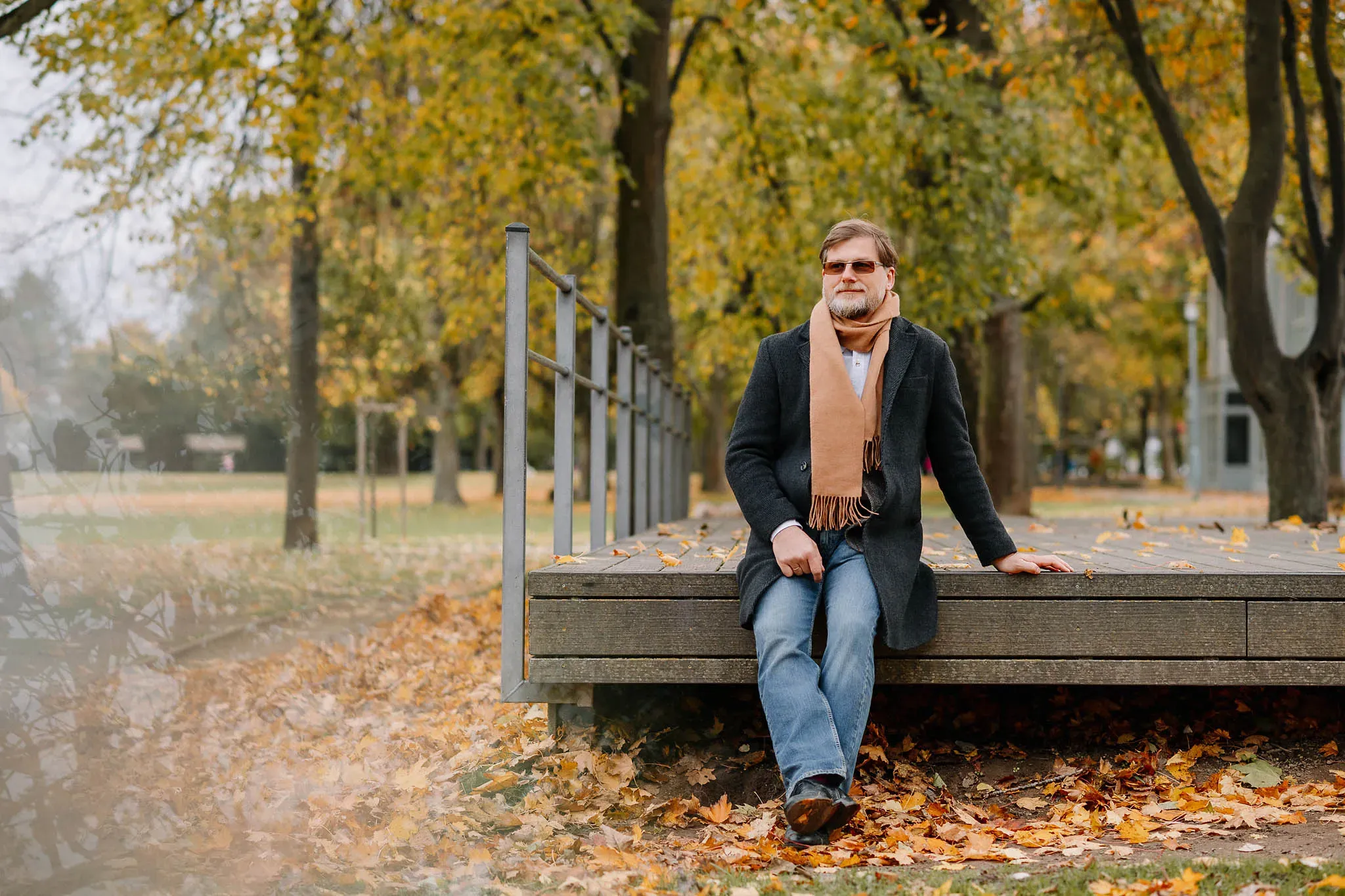 Verträumtes herbstliches Bild von einem Mann im Park mit Herbstlaub